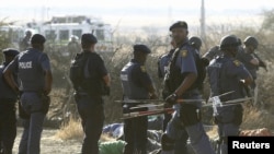 ОАР полициясы оқ тиіп, қаза тапқан адамдардың мәйітіне қарап тұр. 16 тамыз 2012 жыл.