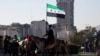 Syria - A man holding a flag adopted by Syria's new rulers rides a horse, after Syria's Bashar al-Assad was ousted, in central Damascus, December 15, 2024. 