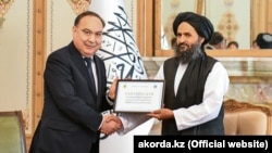 Казакстан президентинин атайын өкүлү Ержан Казыханов (солдо) Абдул Гани Барадарга беш миң тонна гуманитардык жардам сертификатын тапшырды.