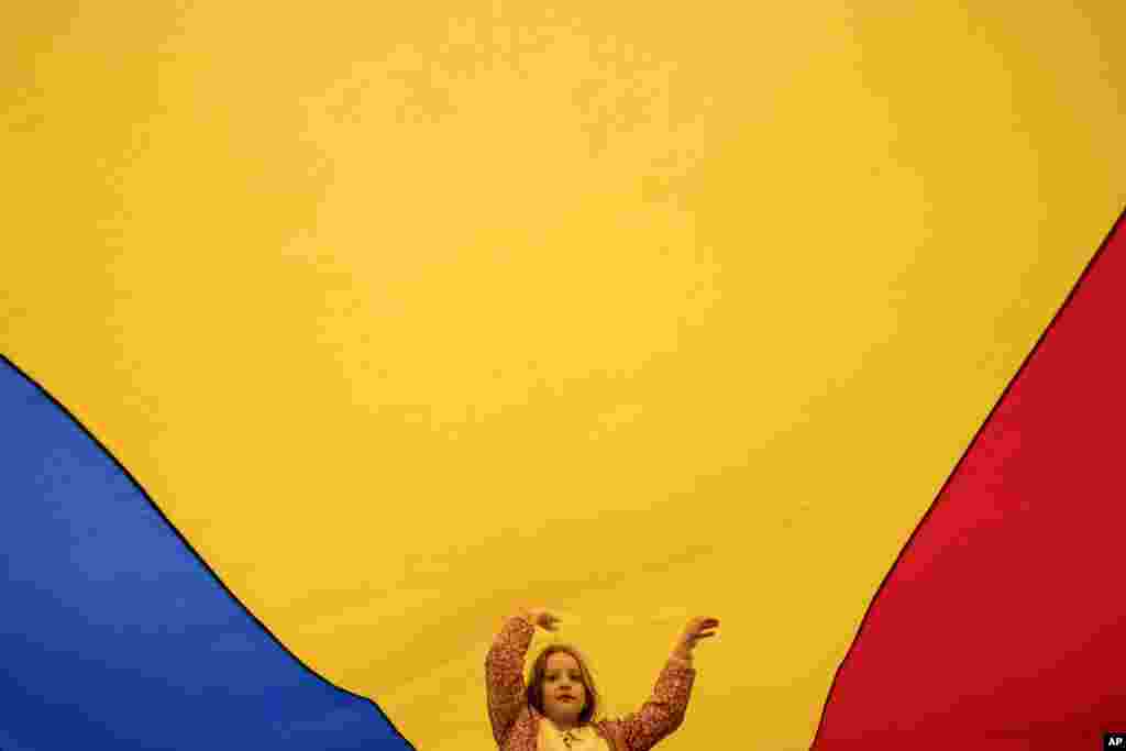 Талаштуу президенттик шайлоонун экичи турунунун астында өткөн Европаны жактаган митингде румын желеги менен ойноп жаткан секелек кыз. Бухарест, 9-май. 