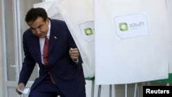 Президент Михаил Саакашвили покидает кабину для голосования на избирательном участке в Тбилиси 1 октября 2012 года. Его партия «Нацдвижение» участвовала в выборах под №5 с 2004 года 