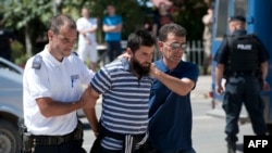 Полицейские Косово ведут в суд подозреваемого в участии в боевых действиях в Сирии. Приштина, 12 августа 2014 года.