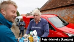 Жонсон үйүнүн жанында турган журналисттерге чай сунуштап жатат, 12-август 2018-жыл.