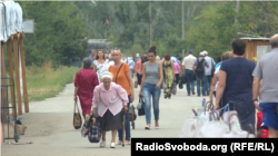 Люди пішки перетинають зруйнований міст, везучи продукти