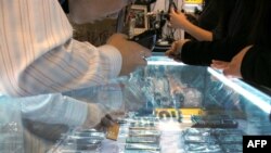 Сүрөт:  Бээжинде Ай-Фонго (iPhone) окшотуп сырты жалтырак, ичи калтырак жасалган аспаптар сатылып жаткан жайма базар. 2009-жылдын 28-октябры.