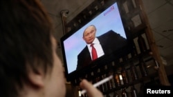 Дондогу Ростов шаарынын тургундары Владимир Путиндин сөзүн кафеде сыналгы аркылуу угууда. 2010-жылдын 16-декабры.