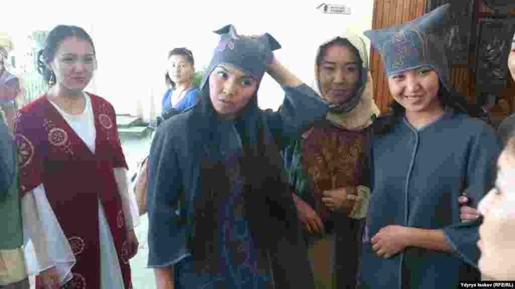 Улуттук кийимдердин модасын көрсөтүүгө даярданып жаткан кыздар.