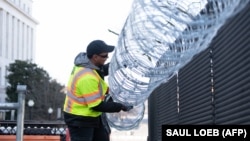 Установка колючей проволоки над ограждением у Капитолия в Вашингтоне.  14 января 2021 года. В США усиливают меры безопасности в преддверии инаугурации Джо Байдена.