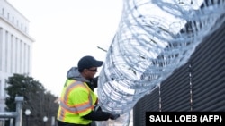 Установка колючей проволоки над ограждением у Капитолия в Вашингтоне.  14 января 2021 года. В США усиливают меры безопасности в преддверии инаугурации Джо Байдена.