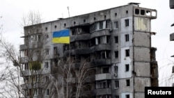 A Ukrainian national flag flies in front of a destroyed residential building in Borodyanka on February 18.