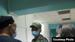 Kenzhebek Abishev (left) pictured with a law enforcement officer and his lawyer