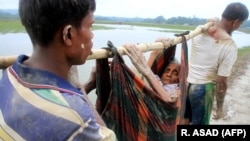 Бангладешке качкан рохинжа мусулмандары карыган кемпирди көтөрүп баратышат.  3-сентябрь, 2017-жыл