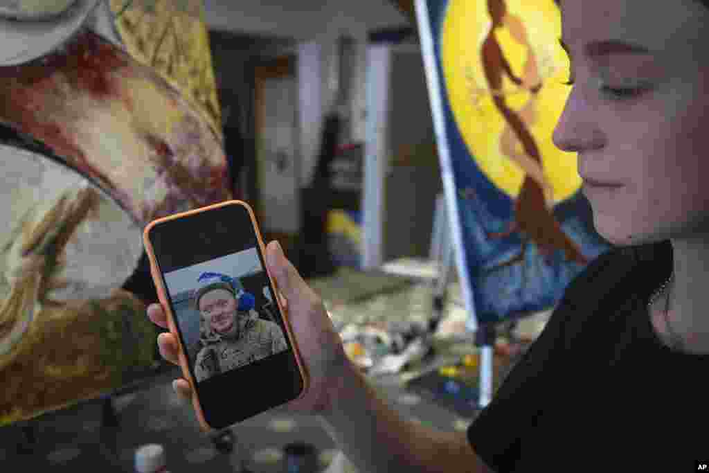 Olesia Skalska shows a photo of her husband, Roman Skalskiy, who was killed in a battle with Russian troops.&nbsp; Skalska came to the art studio with Farion, whom she met at a cemetery,&nbsp;a place where Ukrainian widows commonly find solace in each other&rsquo;s company and form friendships based on shared grief. Skalskiy, 26, had&nbsp;voluntarily joined the military without prior combat experience. The couple was supposed to celebrate their first wedding anniversary in June. But instead, Skalska works on a painting -- the only place where they can be together again. &ldquo;A man is carrying a girl across a field of wheat that has been cut, and I imagine that he is carrying her so that she does not prick her legs,&rdquo; says Skalska, 24, describing her artwork.