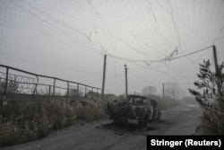 Сожженный пикап под разорванной антидроновой сеткой на дороге вблизи прифронтового города Гуляйполе. Запорожская область, 14 ноября 2025 года