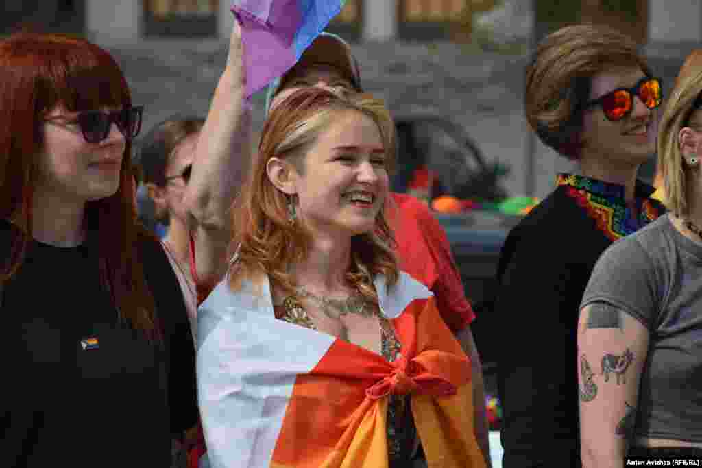 Учасниця автопробігу, загорнута у веселковий прапор, під час мітингу на центральній площі міста