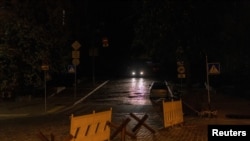 Автомобіль їде темною вулицею, під час часткових відключень електроенергії у Києві, Україна, 16 травня 2024 року