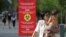 Люди проходят мимо плаката с информацией о мерах профилактики коронавирусной инфекции. Алматы, 12 июля 2020 года. REUTERS/Pavel Mikheyev.