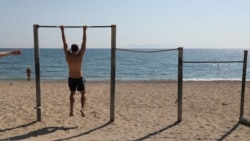 Мужчина делает упражнения на турнике на пустынном пляже в Афинах (Греция). 28 апреля 2020 года.