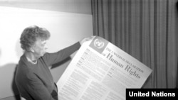 Элеонора Рузвельт декларациянын испан тилиндеги тексти басылган плакатты кармап турат. 1949-жыл.