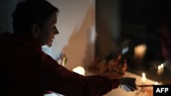 Жителька Чернігова запалює свічки під час відключення світла після російської атаки, жовтень 2025 року