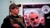 یک عضو حشد الشعبی، گروه شیعهٔ مورد حمایت جمهوری اسلامی، در کنار عکس قاسم سلیمانی، فرماندهٔ پیشین نیروی قدس سپاه پاسداران