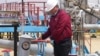 Рабочий крутит кран на нефтепроводе в западном регионе Казахстана