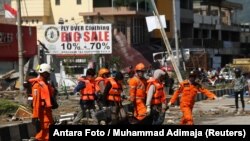 Куткаруучулар адам сөөгүн көтөрүп бара жатышат. Палу шаары. 29-сентябрь, 2018-жыл.