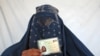 An Afghan woman shows her voter registration card.