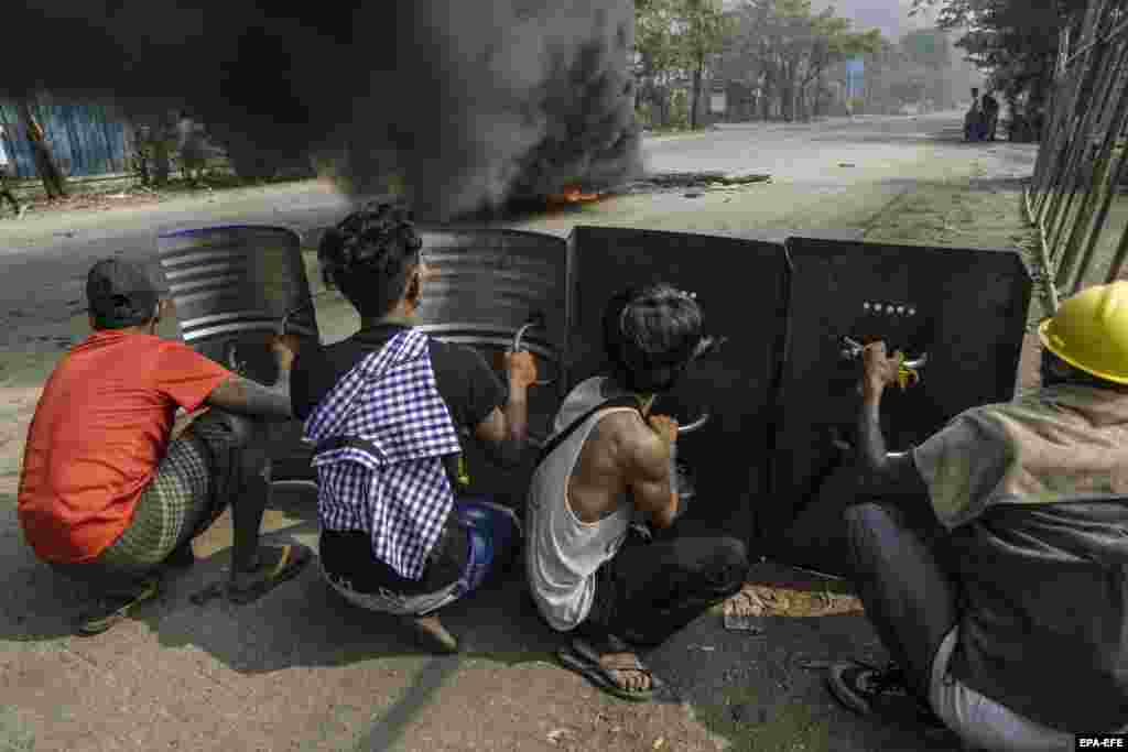 Демонстранттар Янгон шаарынын чет жакасындагы Хлаингтая (Хлаинг Тхаряр) шаарчасында темир калкандарга жашырынып турушат. Бирма. 2021-жылдын 14-марты.