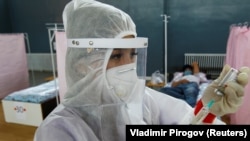 Казакстанда коронавирус менен ооругандарга ийне сайганга камынып жаткан медкызматкер.