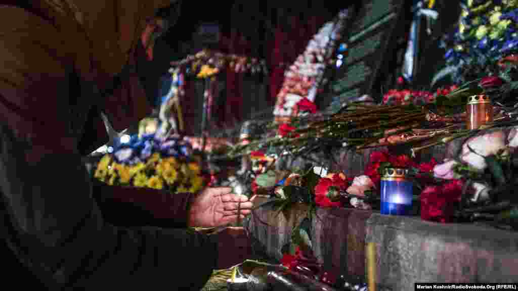 Дівчина запалює свічку перед меморіальної дошкою на вулиці Інститутській