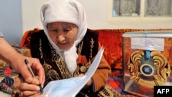 Женщине помогают поставить отметку в избирательном бюллетене в день голосования на досрочных выборах президента Казахстана. Алматинская область, 3 апреля 2011 года.