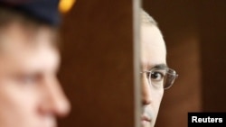 Russia -- Mikhail Khodorkovsky (R) looks out of the defendant's cage as he attends a court session in Moscow, 19Oct2010