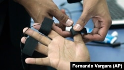 Паліграфоляг накладвае электроды на пальцы паддосьледнага ў Багаце, Калюмбія. 12 чэрвеня 2007 году