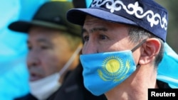 Мужчина в защитной маске с флагом Казахстана на митинге оппозиции в Алматы. Казахстан, 27 марта 2021 года. 