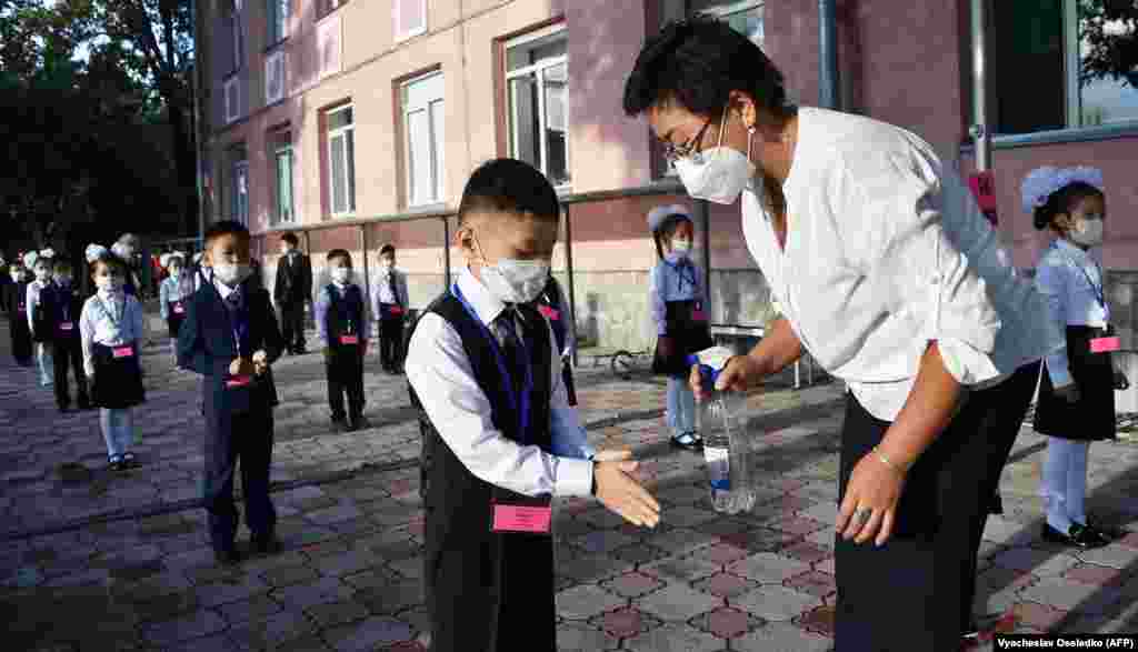 A teacher disinfects the hands of Kyrgyz schoolchildren on the first day of class in Bishkek on September 1. Only first-graders in Kyrgyzstan will study at school from September 1; other grades will attend classes online from home.&nbsp;