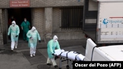 Коронавирустан көз жумган адамдын сөөгүп алып бараткан медкызматкерлер. Испания. 25-март, 