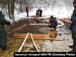 Пад вадой працуе дайвэр, вычышчаючы дно з дапамогай помпы