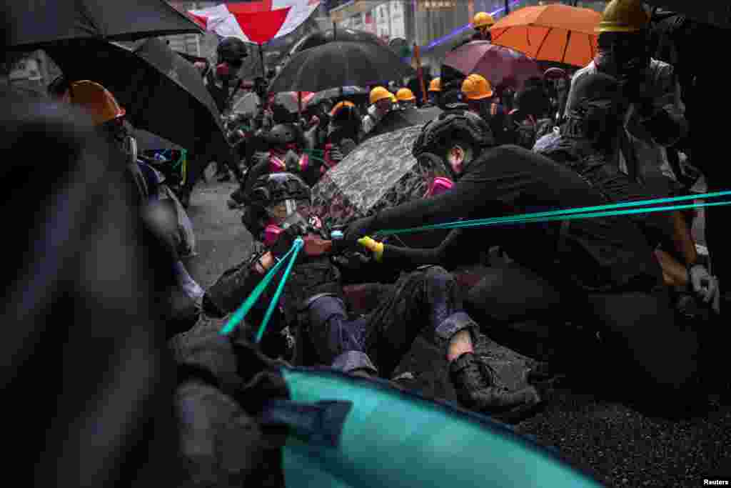 Митингчилер атайын бөлүктүн кызматкерлерине каршы желим ача (рогатка) колдонууда. 25-август, 2019-жыл.&nbsp;&nbsp;