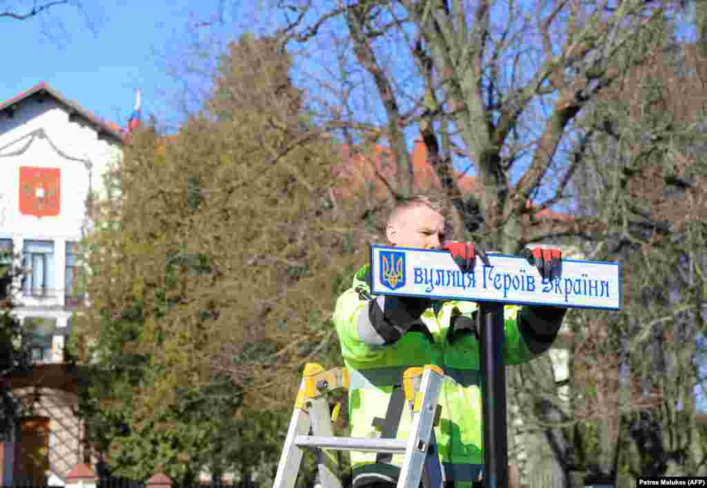 Рабочий устанавливает дорожный знак на украинском языке после переименования улицы, ведущей к российскому посольству (оно на заднем плане) в Вильнюсе (Литва). Март 2022 года. Теперь это улицы Украинских Героев