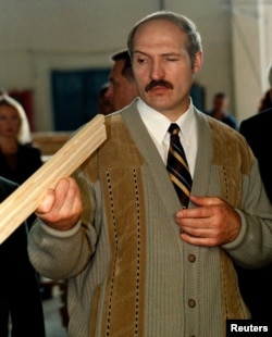 Президент Беларуси Александр Лукашенко смотрит на рейку во время посещения деревообрабатывающего завода в Вилейке. 19 августа 1999 года.