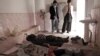 The bodies of a girl and a boy who were killed in an acid attack are watched over by two men in a room in the main hospital of Ghazni city on March 30.