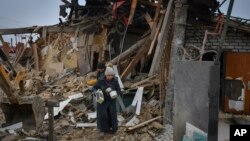 Residents carry their belongings as they leave their home, which destroyed by a Russian rocket attack on the previous day, in Zaporizhzhya on January 1.