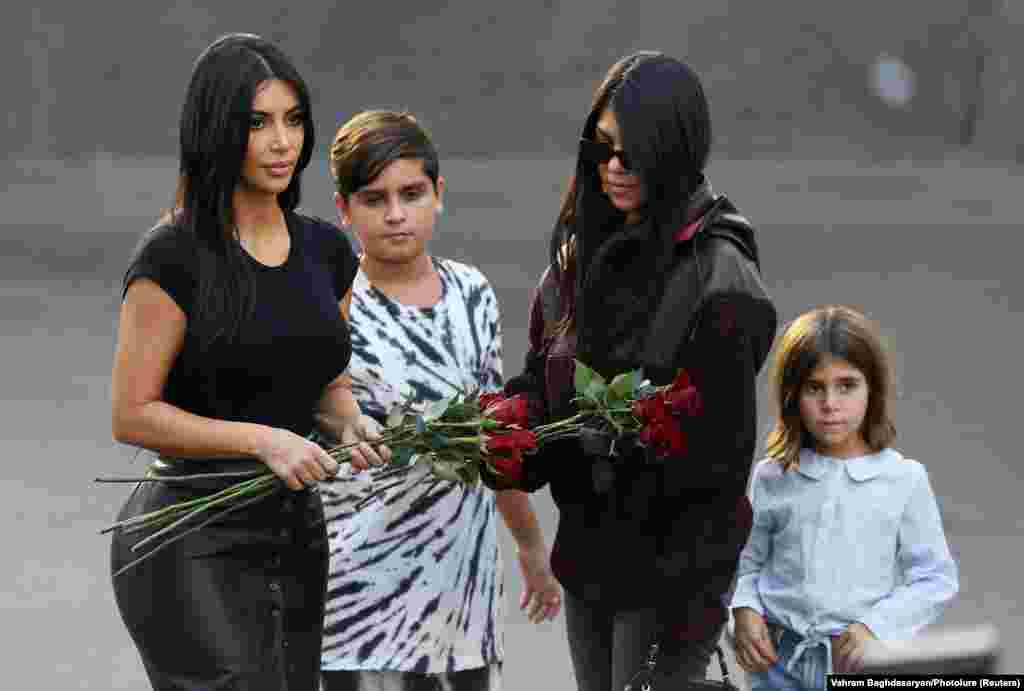 Кім (ліворуч) та її старша сестра Кортні зі своїми дітьми Пенелопою (праворуч) та Мейсоном готуються покласти квіти до меморіалу