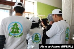 Молодые люди в футболках с надписью "Я за Кок-Жайляу" (то есть за курорт) собрались и слушают женщину в костюме перед началом слушаний. Алматы, 25 февраля 2014 года.