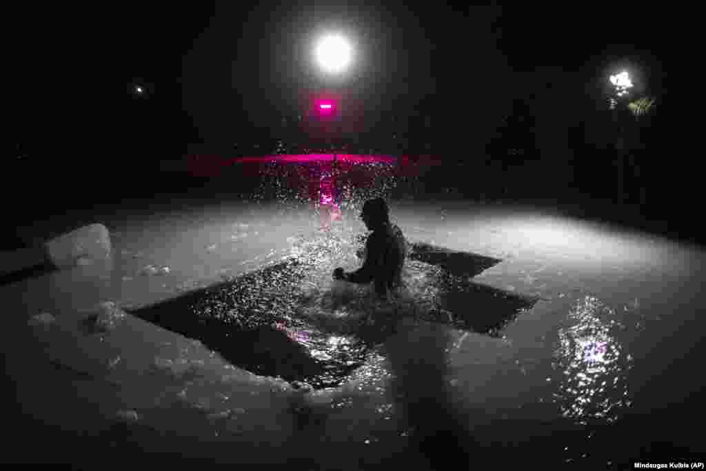 Литовський православний купається у крижаній воді невдовзі після опівночі в озері неподалік литовської столиці Вільнюса