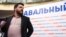 Леонид Волков на фоне баннера избирательной кампании Алексея Навального