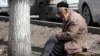 Пожилой человек сидит у дороги в Алматы. Иллюстративное фото.