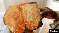 Музейдин кызматкери Ахмед Баба борборунда өрттөн калган байыркы кол жазманы карап жатат. 29-январь