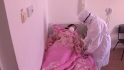 Медик в защитном костюме подходит к пациенту в клинике для больных COVID-19 и «пневмонией».